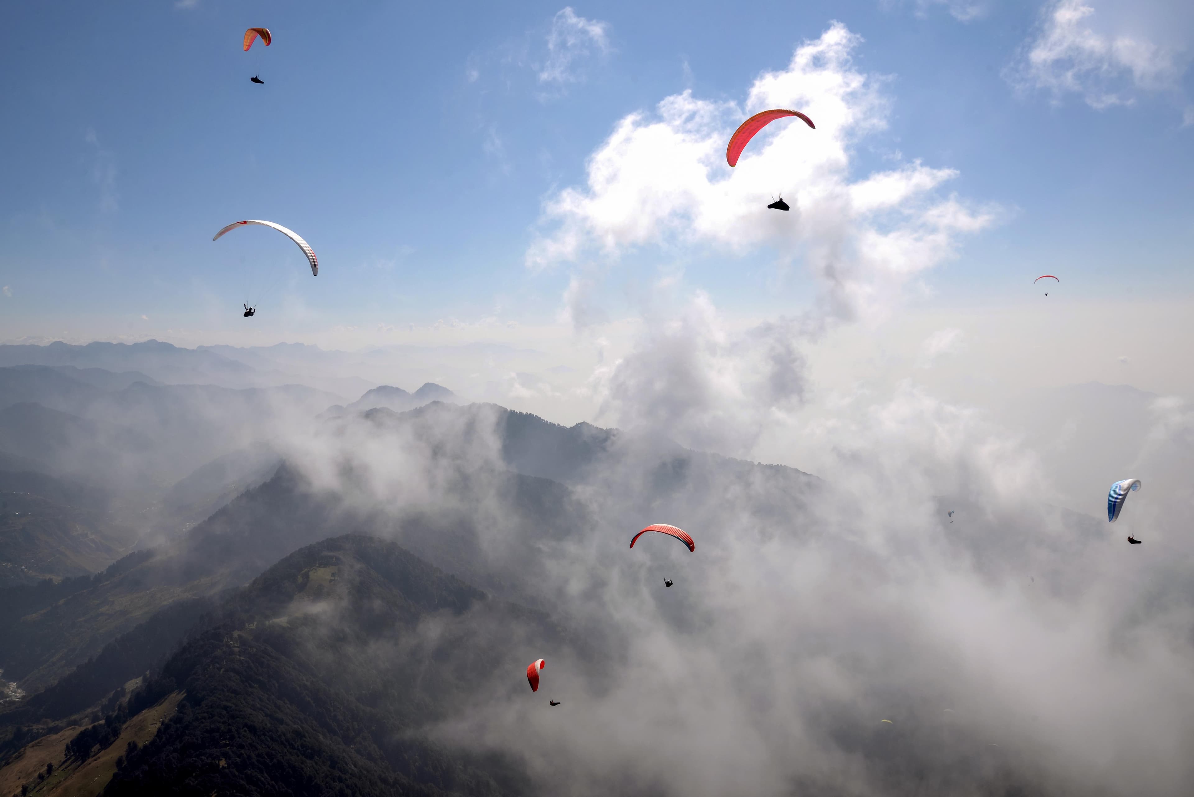 Paragliders moving through mountain clouds