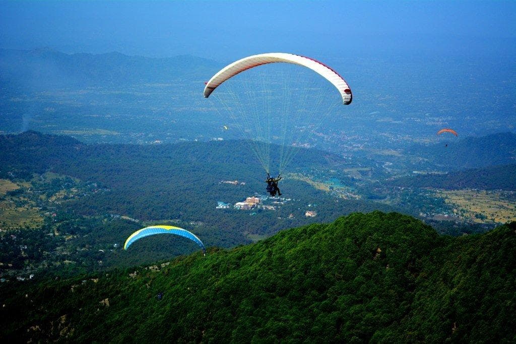 Paragliding above green Himalayan ridges