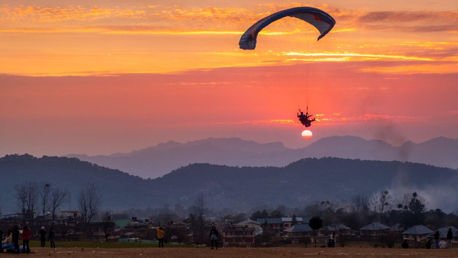A paraglider crossing a Himalayan sunset